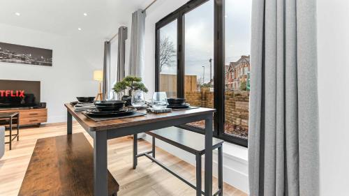 a dining room with a table and large windows at JD Apartments - Urban Retreat with Patio in Croydon
