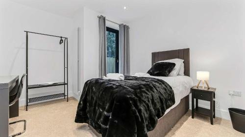 a bedroom with a bed with a black blanket on it at JD Apartments - Urban Retreat with Patio in Croydon