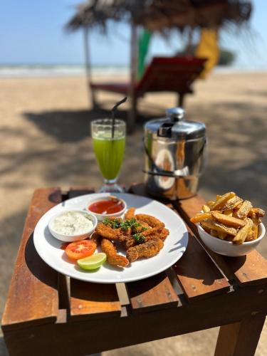 a plate of food on a table with a drink at Lucky Monkey Inn and Restaurant in Weligama
