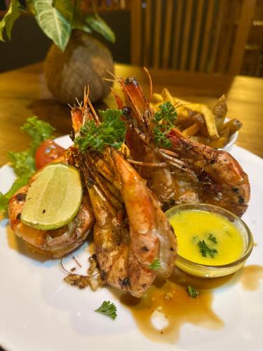 a plate of food with shrimp and a side of sauce at Lucky Monkey Inn and Restaurant in Weligama