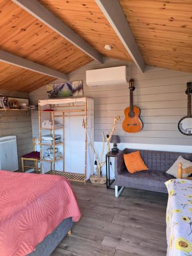 sypialnia z łóżkiem i gitarą w obiekcie Le Chalet des Dany w mieście Saint-Mamert-du-Gard