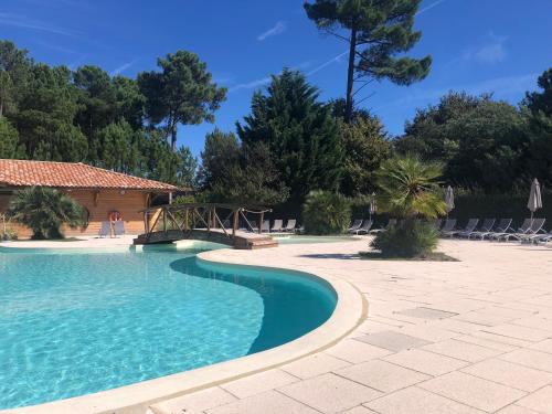einen Pool mit einer Brücke, Stühlen und Bäumen in der Unterkunft Chez Marielle in Parentis-en-Born