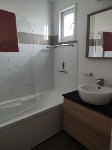 une salle de bain avec une baignoire, un lavabo et un miroir dans l'établissement Chez Marielle, à Parentis-en-Born