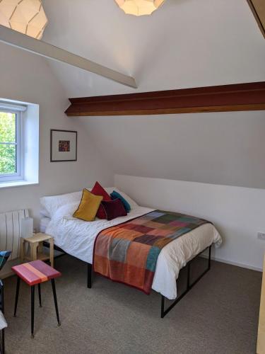 a bedroom with a bed with colorful blankets and pillows at Browhill Loft - contemporary, handcrafted studio in Danehill