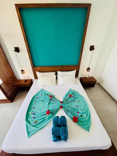 a bed with a green bow tie on it at Villa LA Kurumba in Ambalangoda