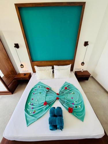 a bed with a green bow tie on it at Villa LA Kurumba in Ambalangoda