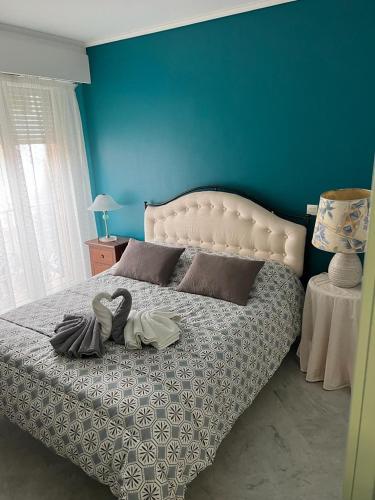 une chambre avec un grand lit avec un mur bleu dans l'établissement Le Victoria Beach, à Menton