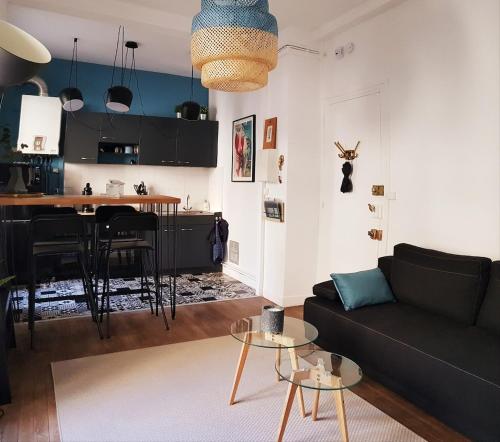 un salon avec un canapé noir et une cuisine dans l'établissement Saint Malo Intra-muros Appart T2, all on foot!, à Saint-Malo