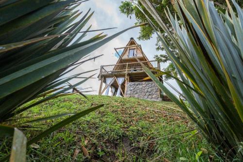 a small building on top of a hill with grass at La Herradura lodge in Santa Rosa de Cabal