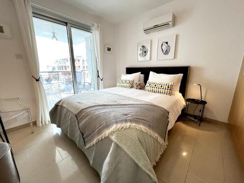 a bedroom with a bed and a large window at STAY Chromata Lagoon Apartment in Protaras