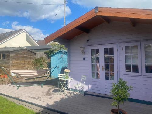 a house with a porch with a hammock on a deck at Little Pink Cabin in Church End