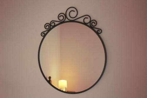 a mirror hanging on a wall with a candle at Miguas House in Baião