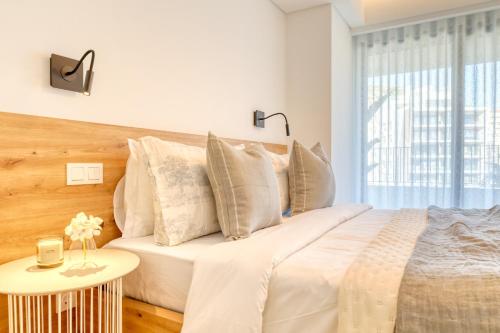 a white bedroom with a large bed with a table at Funchal Acqua Blue 8E, a Home in Madeira in Funchal