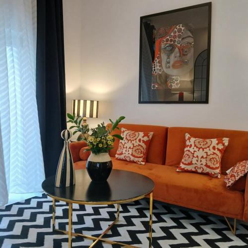 a living room with a orange couch and a table at Beautiful penthouse with terrace next to the Cathedral in Cádiz