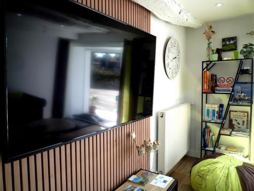 un salon avec une grande télévision à écran plat sur un mur dans l'établissement Gite Le Prédaïou 4 personnes, à Montrozier