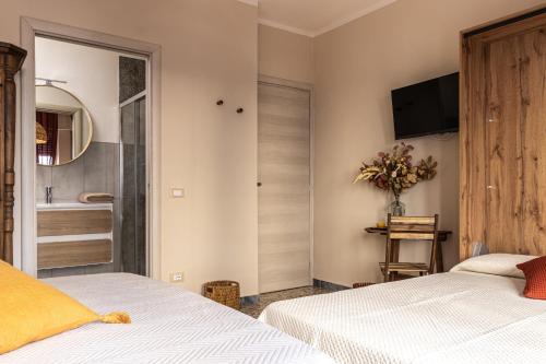 a bedroom with two beds and a television on the wall at L'Erika in Città in Livorno