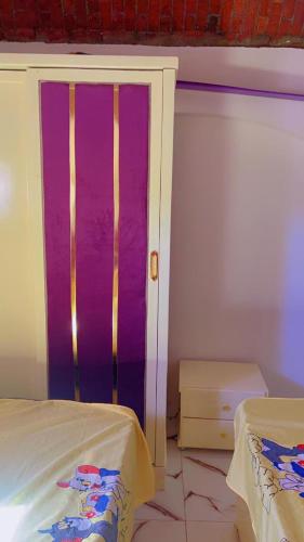 a room with a bed and a purple wall at tmem home in Jazīrat Aswān