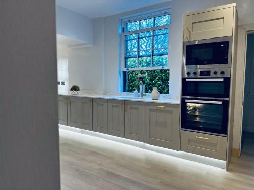 a kitchen with a sink and an oven and a window at Red Roofs - 5BR Luxury - Large Gardens - EV Point - Near Edinburgh in Newtongrange