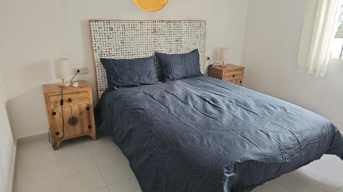 a bed with a blue comforter and two night stands at Los altos 1 in Los Altos