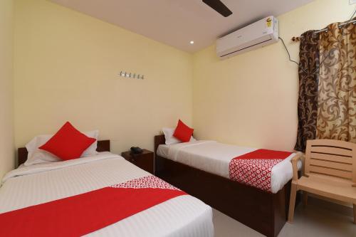 a bedroom with two beds with red and white sheets at Hotel O Andhra Pradesh Hotels Association in Vijayawada