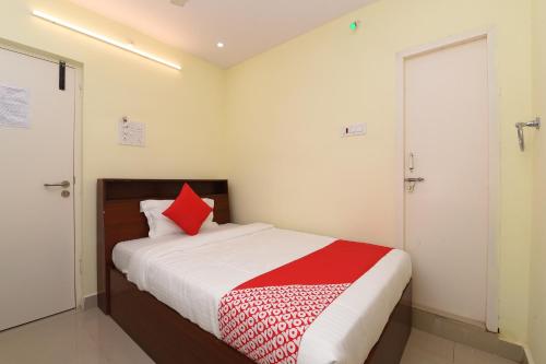 a bedroom with a bed with a red pillow at Hotel O Andhra Pradesh Hotels Association in Vijayawada