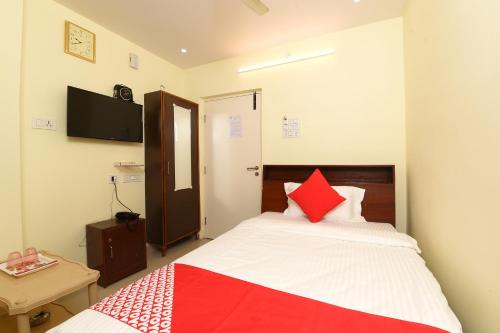 a bedroom with a bed with red and white pillows at Hotel O Andhra Pradesh Hotels Association in Vijayawada