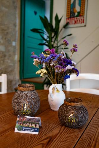 two vases sitting on a wooden table with flowers at Gite Les 3M in Baugy