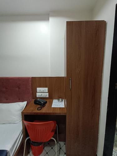 a desk in a room with a bed and a red chair at Best Hotel in Mumbai