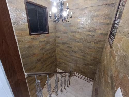 a staircase with a stone wall and a chandelier at Best Hotel in Mumbai