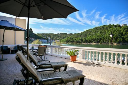 a balcony with chairs and an umbrella and a river at Apartment Bazdaric in Novigrad Dalmatia