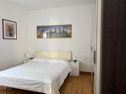 a white bedroom with a bed and a picture on the wall at Appartamento spazioso con 3 camere da letto in Riva del Garda