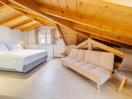 a bedroom with a bed and a couch and wooden ceilings at Nymfes Corfu Apartments in Corfu Town