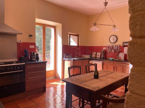 une cuisine avec une table en bois au milieu dans l'établissement Maison viticole dans le Sud de la France avec grand piscine, à Moussan
