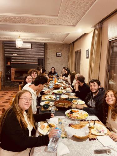 a group of people sitting at a long table eating food at Canyon Dades Guest House in Akedim Msemrir