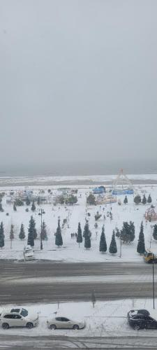 a snow covered parking lot with cars and trees at Sea View House in Sumqayyt
