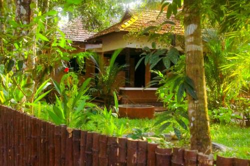 a small house in a garden with a fence at Mannarasala Bilva homestay Allappey in Alleppey
