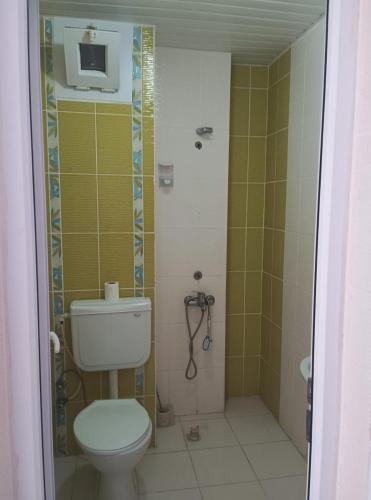 a bathroom with a toilet and a tv on the wall at Duygu Otel Konaklama in Karatas