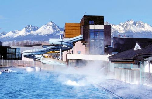 a water slide in a resort with mountains in the background at Penzion Plesnivec in Poprad