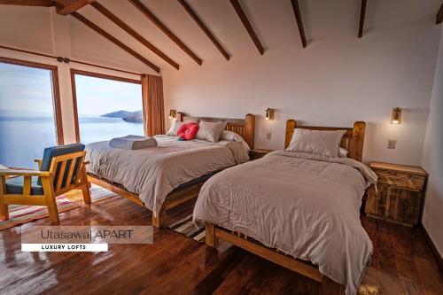 two beds in a room with a large window at Utasawa Loft APART in Comunidad Yumani
