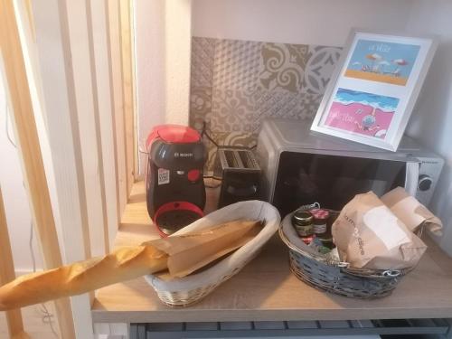 een tafel met een magnetron en een mandje erop bij Cozy duplex en RDC hyper centre le Mans gare circuit des 24h in Le Mans