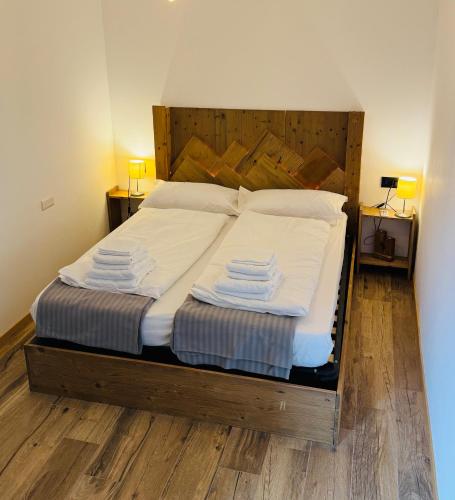 a bedroom with a large bed with white sheets and pillows at La Fenestra Cadore - Dolomiti in Pieve di Cadore