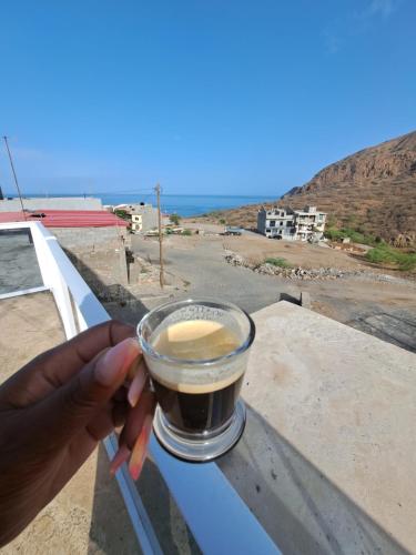 a hand holding a cup of coffee on a ledge at Casa Graciosa in Tarrafal