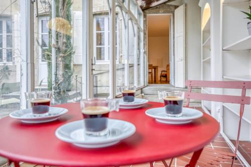 une table rouge avec trois tasses de café dessus dans l'établissement Bedroom 2 - Authentic charm - COLIVING Historic House, à Ferney-Voltaire