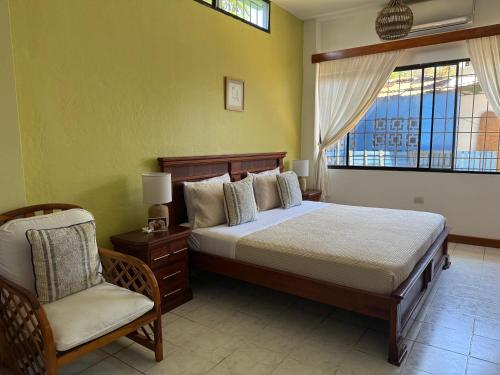 a bedroom with a bed and a chair and a window at Mare Mio in Puerto Baquerizo Moreno