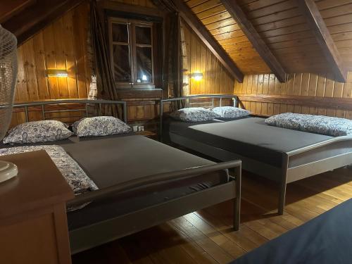 three beds in a room with wooden walls at Cottage Plavi Lav Potok in Potok