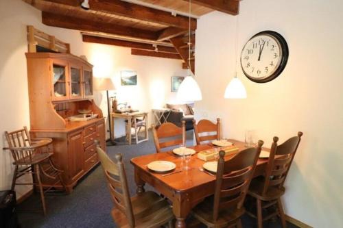 une salle à manger avec une table et une horloge au mur dans l'établissement Trésors de Lilain, à Cheylade