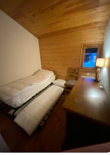 Cette petite chambre comprend deux lits et un bureau. dans l'établissement Appartement aux Houches Pied des pistes, aux Houches