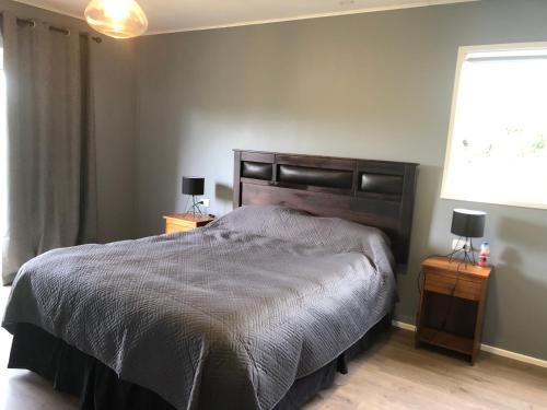 a bedroom with a bed and two night stands with lamps at Casa en Frutillar in Frutillar