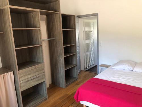 - une chambre avec des étagères en bois et un lit avec une couverture rouge dans l'établissement DOMAINE NATURE Et SENS, à Presly