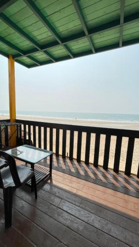a table and a bench on a deck near the beach at Eco Wooden Homes in Benaulim